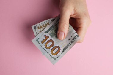 Para değişimi. Pembe arka planda dolar banknotları tutan kadın.