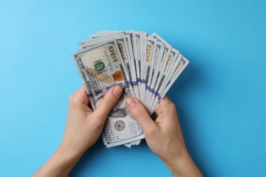 Para değişimi. Açık mavi zemin üzerinde dolar banknotları tutan kadın, üst görünüm
