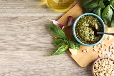 Tabakta pesto sosu, fesleğen, çam fıstığı, ahşap masada peynir ve sarımsak. Metin için boşluk