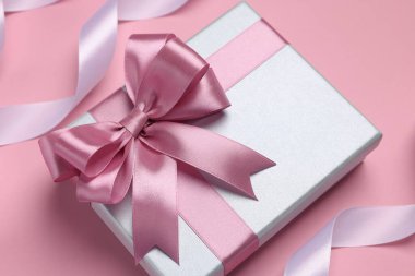 Pembe arka planda kurdeleleri ve rengi olan güzel bir hediye kutusu.