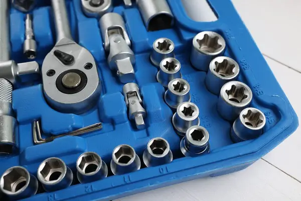 Otomobil tamircisinin beyaz ahşap masadaki plastik kutuda kullandığı aletler.