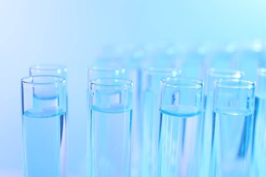 Açık mavi arka planda birçok cam test tüpü, yakın plan