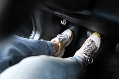 Spor ayakkabılı bir kadın araba frenine basıyor, yakın plan.