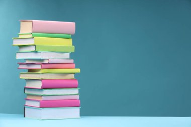 Açık mavi arkaplan üzerine renkli kitap yığını, metin için boşluk