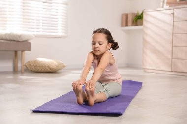 Sevimli küçük kız evde kendini paspasa geriyor.