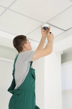 Tornavidalı teknisyen kapalı alanda güvenlik kamerası kuruyor. Düşük açılı.