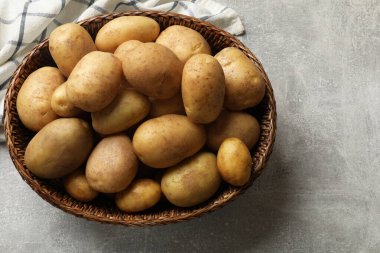 Gri masada sepetin içinde bir sürü taze patates, üst manzara. Metin için boşluk