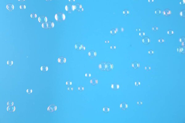 Красивые прозрачные мыльные пузыри на светло-голубом фоне