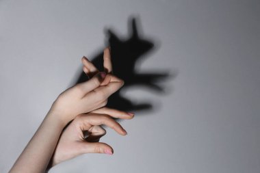 Gölge kuklası. Kadın gri arka planda tavşan gibi el hareketi yapıyor, yakın plan. Metin için boşluk