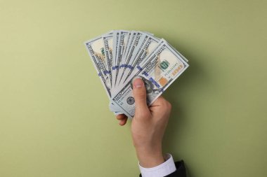 Para değişimi. Zeytin arka planında dolar banknotları tutan adam, üst görünüm