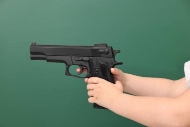 Tahtaya dayalı silahlı bir çocuk, yakın plan. Okul çatışması