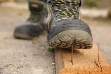 Dikkatsiz işçiler tahta çiviye basıyor, yakın plan.