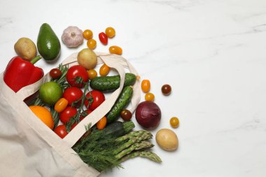 Vejetaryen yemek servisi. Farklı taze sebzelerle dolu çantalar ve beyaz mermer arka planda meyveler. Metin için boşluk