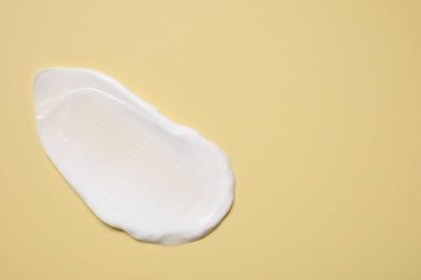 Soluk sarı arka planda yüz kremi, üst manzara. Metin için boşluk