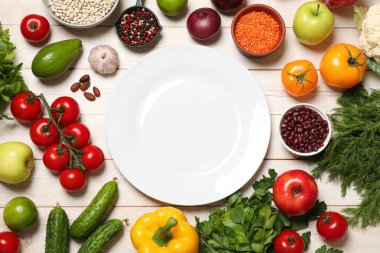 Farklı vejetaryen ürünler ve tabaklar açık ahşap masa, üst manzara.