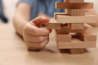 Çocuk içeride ahşap masada Jenga oynuyor, yakın plan.