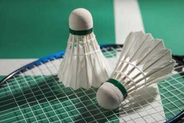 Tüylü badminton mekikleri ve raketleri sahada, yakın plan.