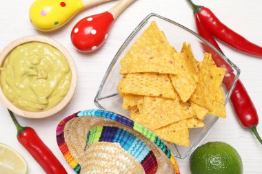 Nachos cipsli nefis guacamole, Meksika şapkası ve marakas beyaz ahşap masa, düz uzanmış