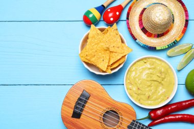 Nachos cipsli nefis guacamole Meksika şapkası, ukulele ve açık mavi ahşap masa üzerinde marakas, düz yatak. Metin için boşluk