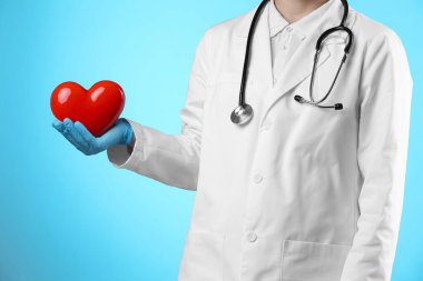 Açık mavi arka planda kırmızı kalpli doktor, yakın plan.