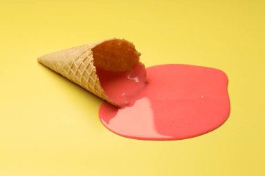 Erimiş dondurma ve sarı arka planda gofret konisi.