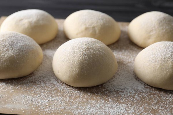 Raw dough balls with flour on table, closeup