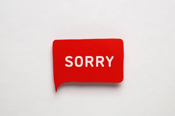 stock image Red paper speech balloon with word Sorry on light background