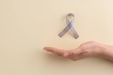 Bej arka planda gri farkındalık kurdelesi olan bir kadın, üst manzara. Metin için boşluk
