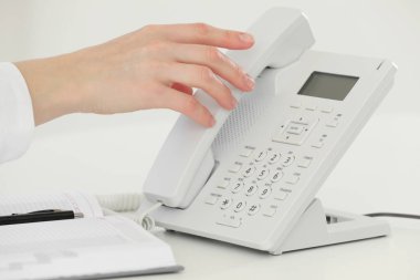 Assistant taking telephone handset at white table, closeup