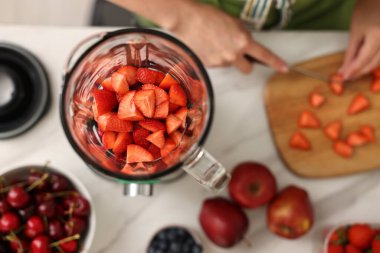 Mutfaktaki beyaz mermer masada blender ile nefis smoothie yapan kadın.