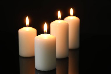 Birçok yanan mum ayna yüzeyinde siyah arkaplana karşı