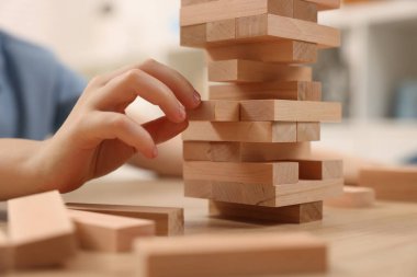 Çocuk içeride ahşap masada Jenga oynuyor, yakın plan.