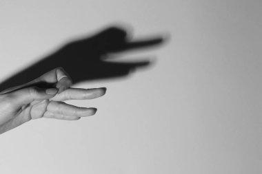 Gölge kuklası. Kadın hafif arka plandaki kaz gibi el hareketi yapıyor, mesaj için yer ararken yakın plan çekiyor. Siyah ve beyaz etkisi