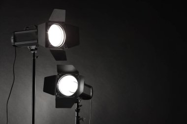 Karanlık fotoğraf arkaplanı ve profesyonel ışıklandırma ekipmanları stüdyoda. Metin için boşluk