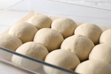 Raw dough balls in baking dish on table, closeup clipart