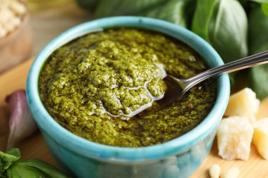 Tabakta pesto sosu, kaşık, peynir ve fesleğen.