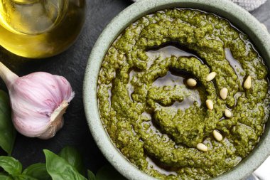 Lezzetli pesto sosu kasede, fesleğende, sarımsak ve yağ siyah masada.