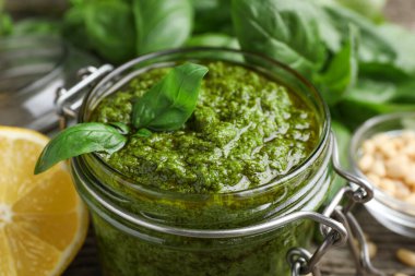 Cam kavanozda lezzetli pesto sosu, masada fesleğen ve limon, yakın plan.