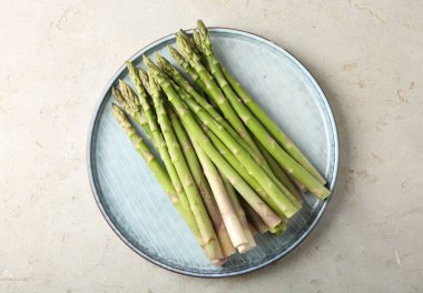 Taze yeşil kuşkonmaz tabağı açık dokulu masa, üst görünüm