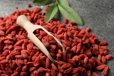 Kurutulmuş kurt üzümü ve kepçeyle gri dokulu masa, yakın plan.