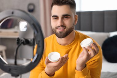 Güzellik blogcusu kozmetik ürünü inceliyor ve akıllı telefon ve halka lambasıyla video kaydediyor.