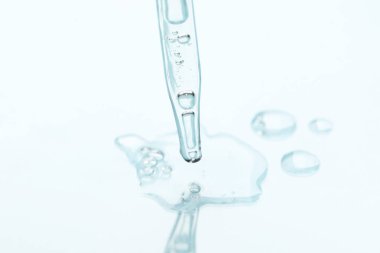 Işık arka planında cam pipet ve şeffaf sıvı, yakın plan