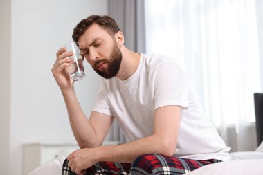 Genç adam sabahları yatakta baş ağrısı çekiyor.