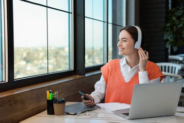 Laptop kullanan genç bir kız öğrenci kafeteryada çalışırken akıllı telefon kullanıyor.