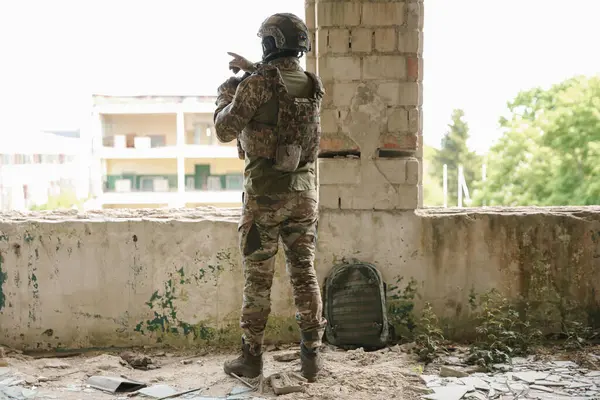 stock image Military mission. Soldier in uniform with binoculars inside abandoned building, back view