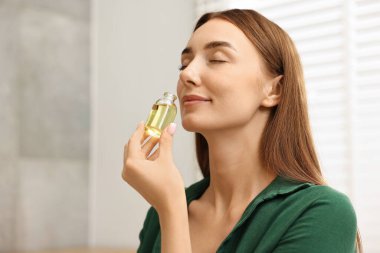 Aromaterapi. Kapalı mekanda bir şişe şarabı olan güzel bir kadın.