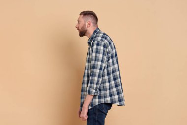 Soluk turuncu arka planda zayıf duruşu olan bir adam.