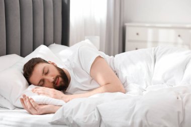 Yakışıklı genç adam, sabahları yatakta uyuyor.