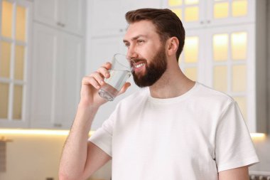 Sabahları mutfakta bir bardak suyla mutlu genç bir adam.