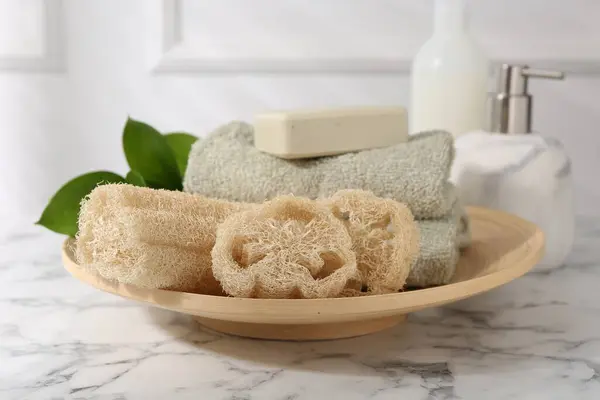 stock image Loofah sponges, soap, towels and green leaves on white marble table